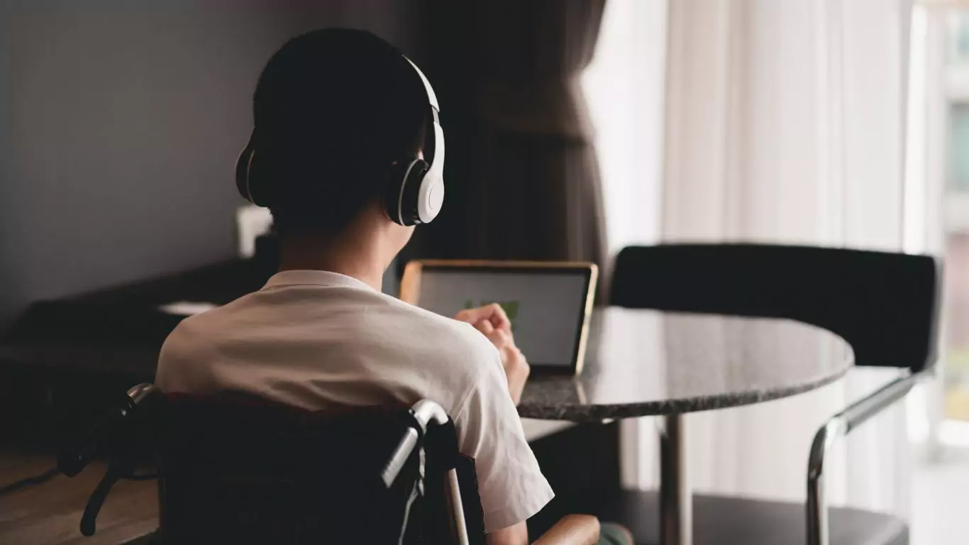 A young man on a wheelchair using a laptop