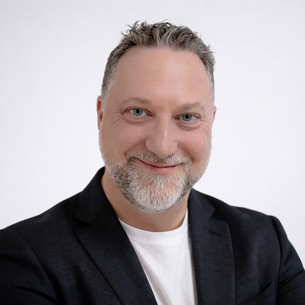Headshot of Jeff Rodgers. Middle-aged white male with short salt-and-pepper hair and beard. He is smiling and wearing a white T-shirt and blue blazer.