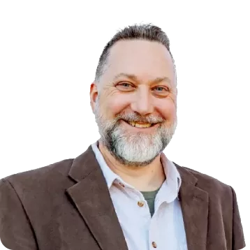White male with short dark hair, white and grey beard. Smiling, he is wearing a brown sport coat and white colored shirt.