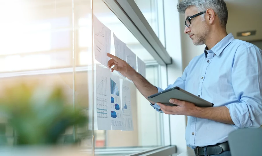A man pointing at a graph while holding a tablet.