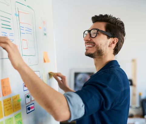 Man wearing glasses organizing information on a whiteboard.