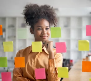 Girl thinking while staring at post-it notes on a glass wall.
