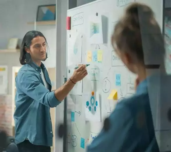 Man pointing to a whiteboard giving a design presentation.