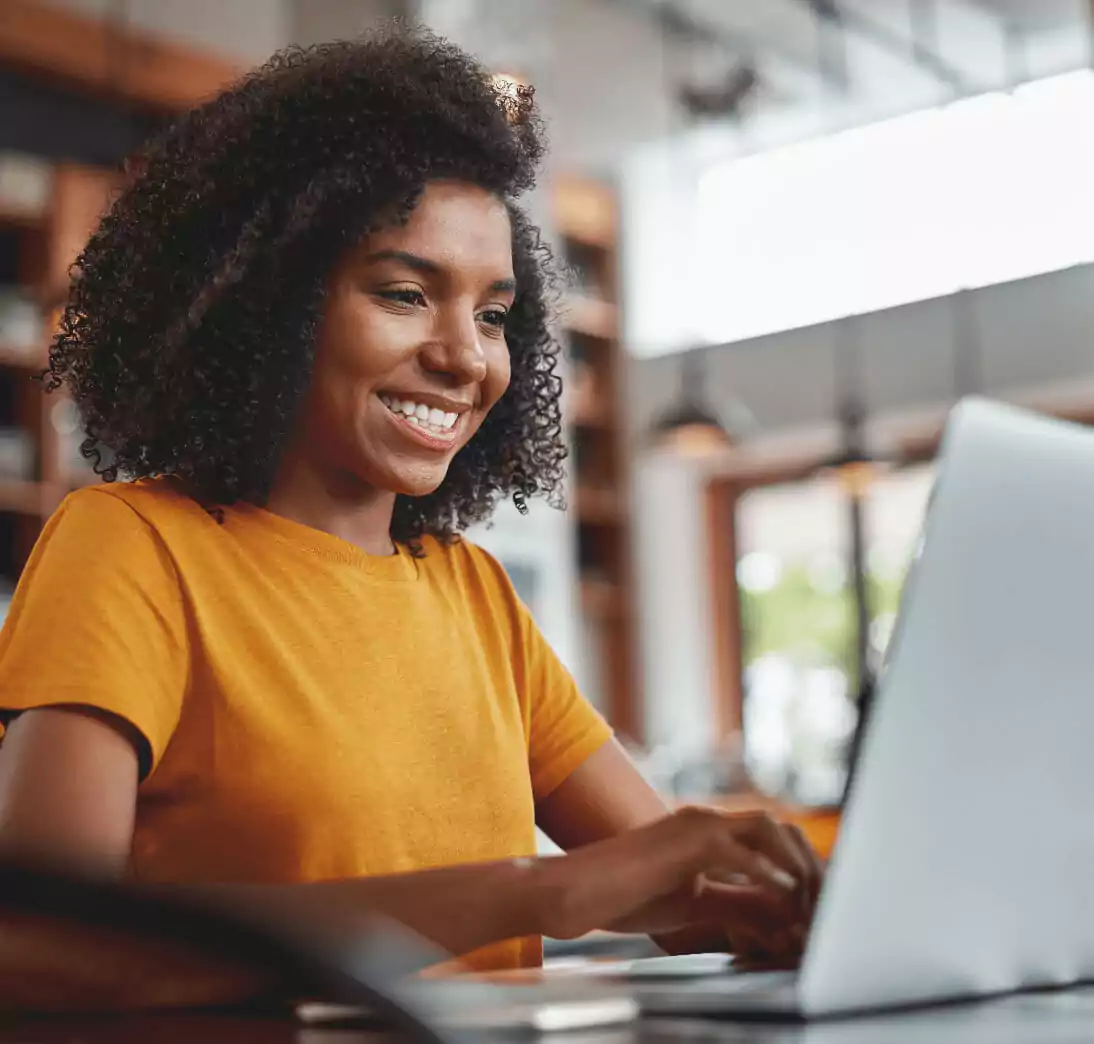 African American woman smiling and looking at her laptop.