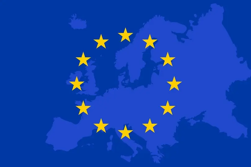 A circle of yellow starts over a field of blue with a lighter blue outline of Europe underneath.